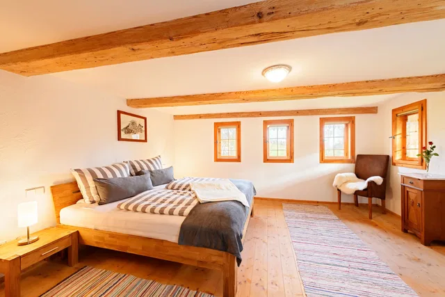 Schlafzimmer mit Doppelbett und drei Fenstern