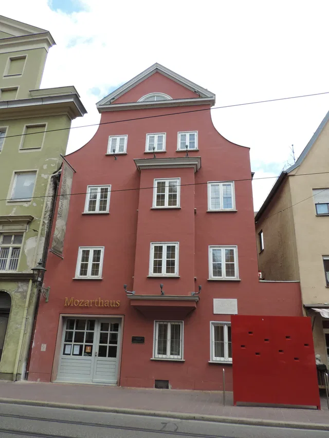 Rosafarbene Fassade des Mozarthauses mit Gedenktafel und Straßenbahngleisen