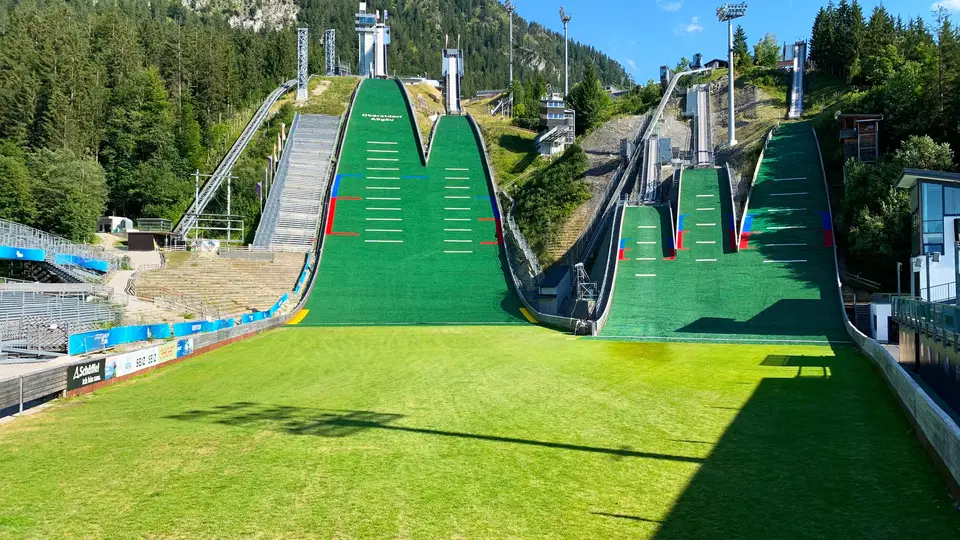Skisprungschanzen in Oberstdorf mit grünen Matten und sommerlicher Bergkulisse.