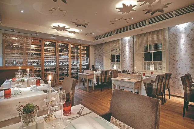 Stilvoller Gastraum des ESS ATELIER Strauss mit gedeckten Tischen und Weinregalen