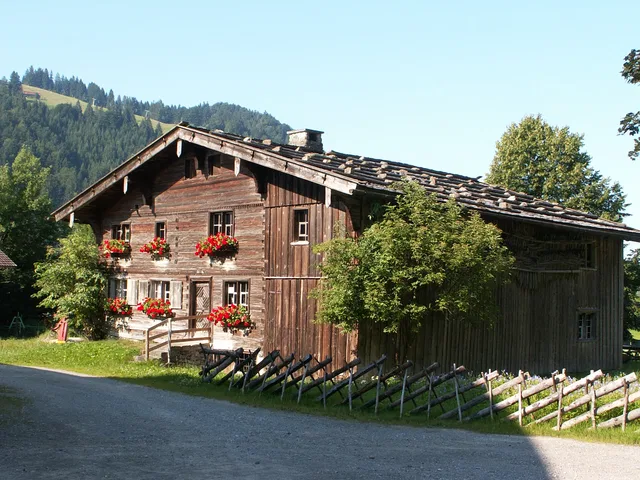 Historisches Holz-Chalet mit Blumenkästen an der Fassade in ländlicher Berglandschaft.