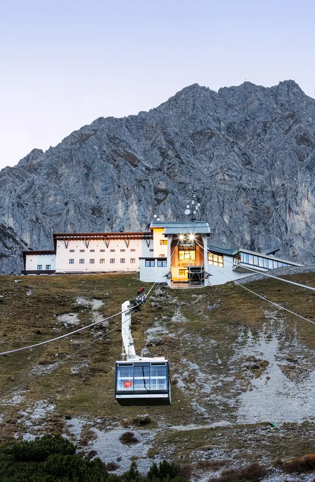 Seilbahnkabine vor einer Bergstation und einer zerklüfteten Felswand