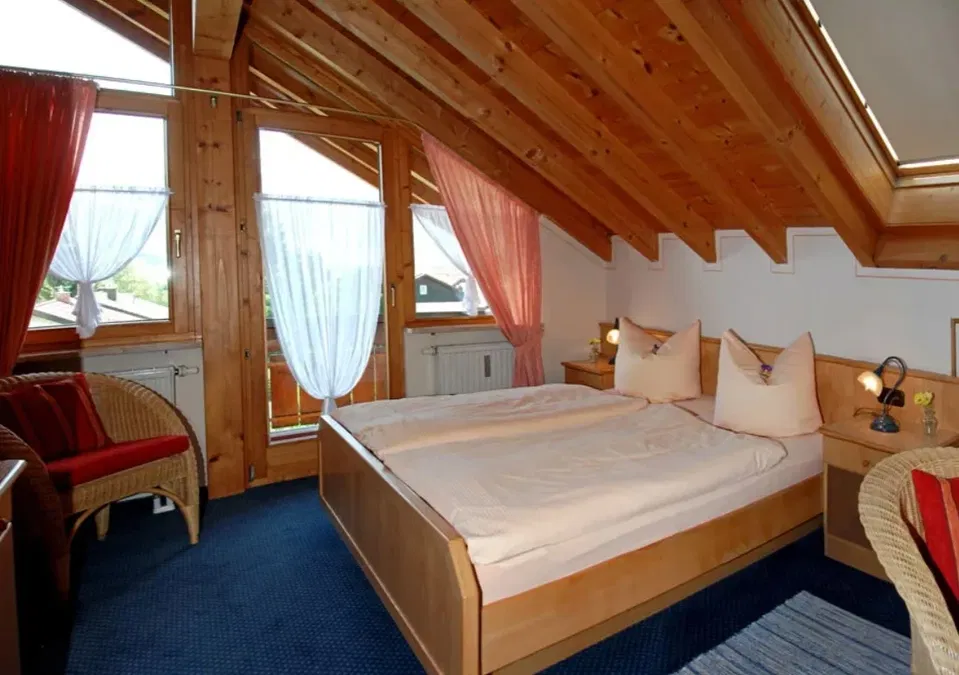 Dachstudio mit Doppelbett, Holzbalken und Sitzbereich