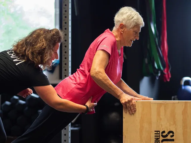Coach unterstützt eine Teilnehmerin beim Training an einer Box