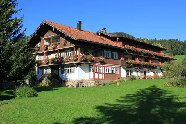 Hotel Mühlenhof mit blumengeschmückten Balkonen und Garten.