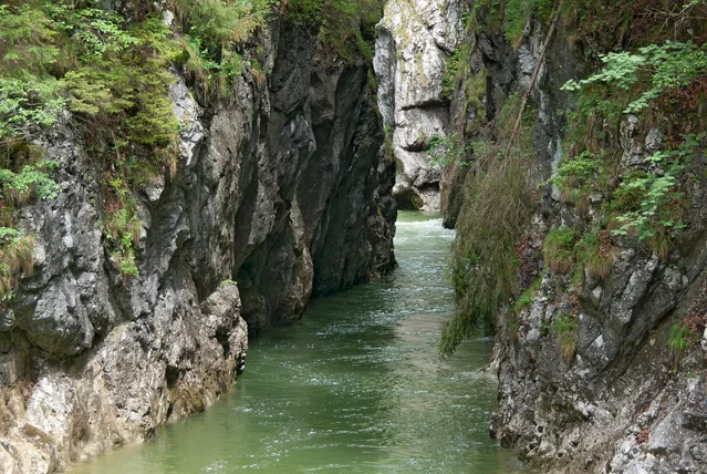 Enge Felsenschlucht mit grünem Wasser dazwischen.