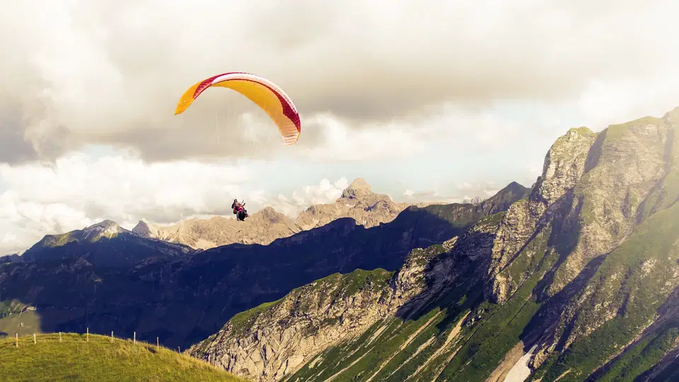Einzelner Gleitschirm über einer alpinen Berglandschaft.