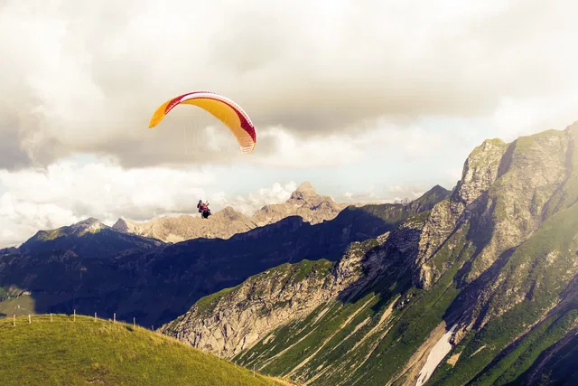 Paraglider mit buntem Schirm über einer felsigen Berglandschaft