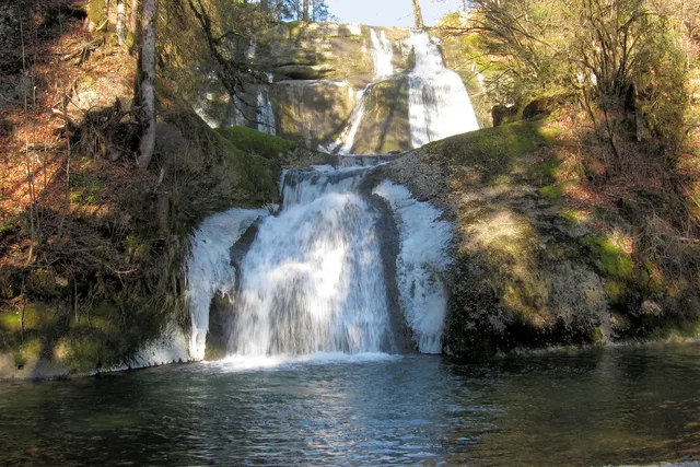 Mehrstufiger Wasserfall im Wald fließt in einen See