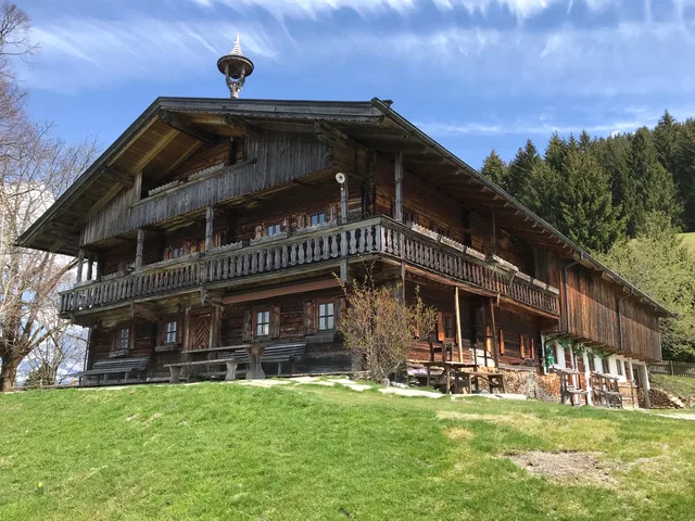 Traditionelles Holzhaus mit Balkonen auf einer Wiese am Waldrand