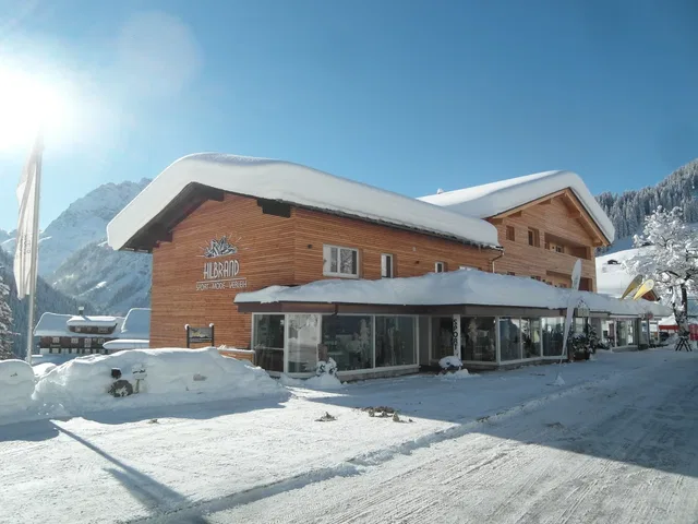 Holzhaus im Winterszenen, verschneite Dächer, sonniger Himmel, alpine Berglandschaft