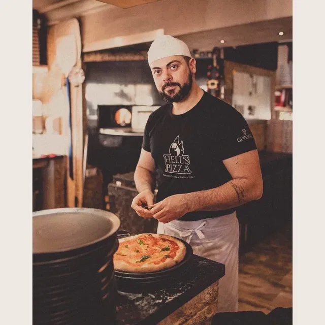 Pizzabäcker mit weißer Mütze am Arbeitsplatz bei Hell’s Pizza