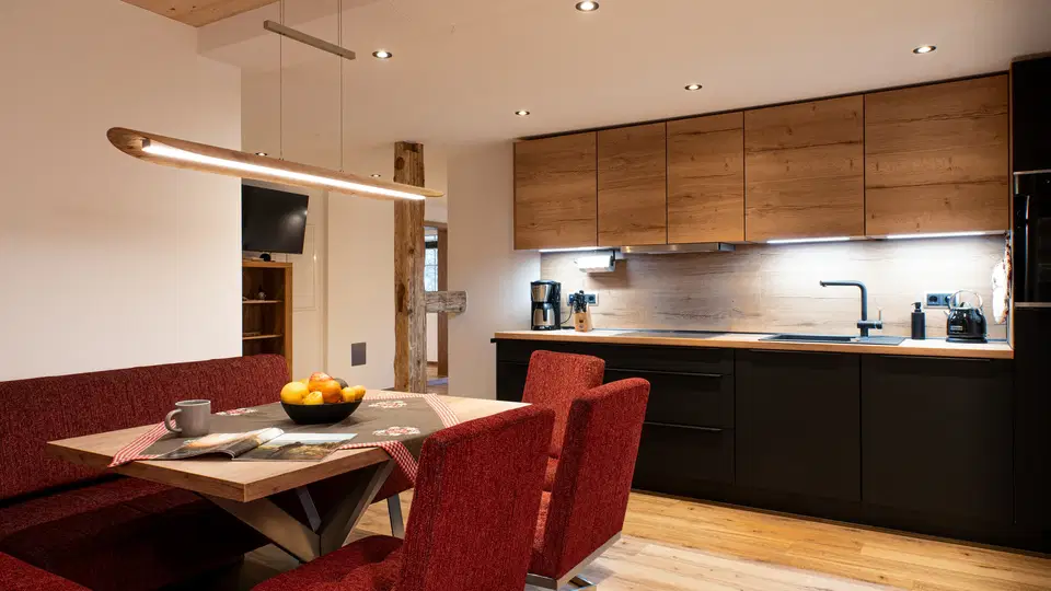 Wohnküche mit Holzfronten und roter Sitzecke im Apartment Hirsch