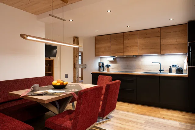 Wohnküche mit Holzfronten und roter Sitzecke im Apartment Hirsch