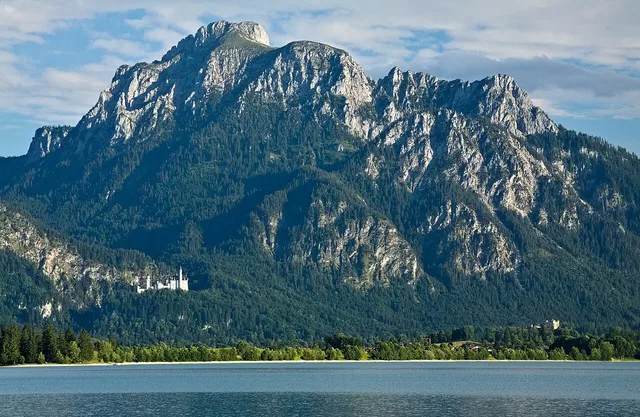 Berglandschaft mit See im Vordergrund, Wald und felsigen Gipfeln