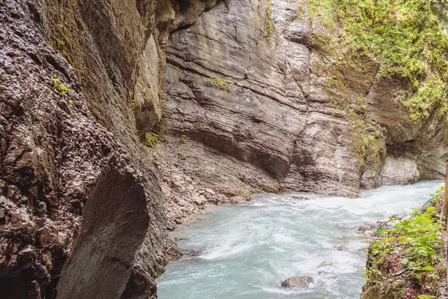 Fluss in einer engen Felsenschlucht mit moosbedeckten Wänden