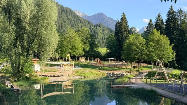 Teich und naturnahe Spielbereiche im WalserPark Riezlern vor der Bergkulisse