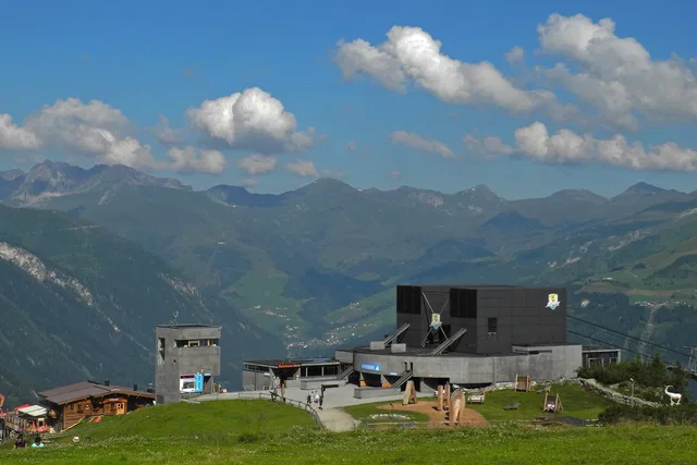 Bergstation auf einer Alm vor einem weitläufigen Alpenpanorama