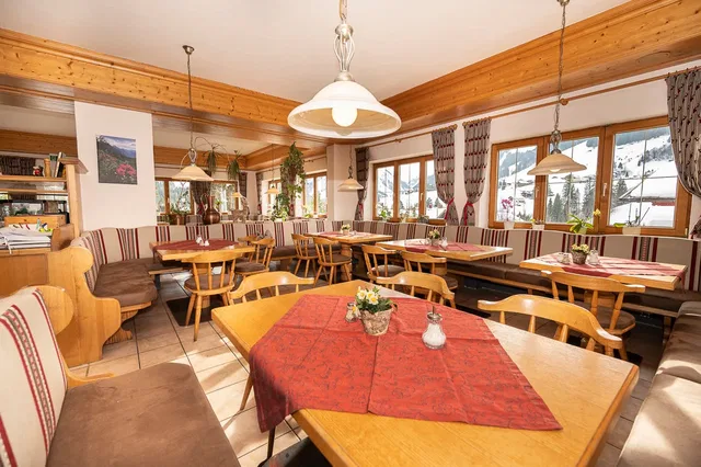 Rustikales Gasthaus-Interieur mit Holzbalken, gepolsterten Bänken und Holztischen.